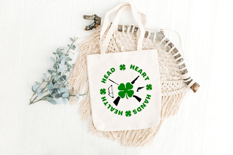 May include: A white canvas tote bag with a green shamrock and the words "Head, Heart, Hands, Health" printed in a circle around it.