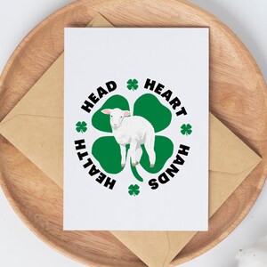 May include: A white card with a green four-leaf clover with a white lamb in the center. The clover has the words "HEALTH", "HEAD", "HEART", and "HANDS" around it.