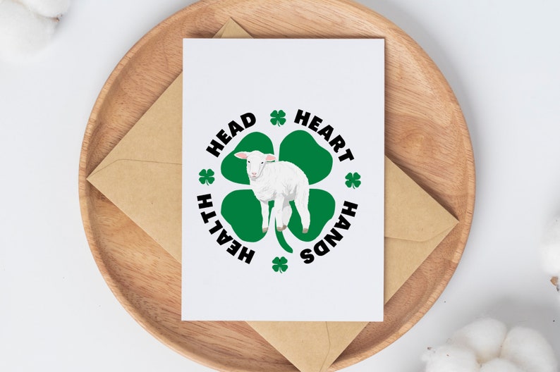 May include: A white card with a green four-leaf clover with a white lamb in the center. The clover has the words "HEALTH", "HEAD", "HEART", and "HANDS" around it.