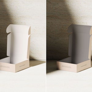 May include: A beige cardboard shipping box with an open lid, featuring a clean interior and the text PACKAGING DESIGN printed on the front panel. The box is presented in two variations, one with a white interior and one with a dark gray interior.