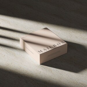 May include: A square, light beige cardboard box featuring the word MAILBOX printed in black serif font on the top surface. The box has additional small black text on the side and top, including the phrase PACKAGING DESIGN.
