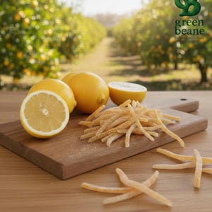 May include: A wooden chopping board holds fresh lemons, one cut in half, and candied lemon peel. The background shows a lemon orchard with the "green beane" logo.