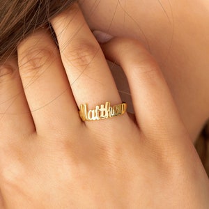 May include: A gold ring with the name "Matthew" spelled out in cursive lettering.