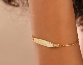 Peut inclure: Bracelet doré avec une plaque rectangulaire gravée du nom "Olivia" et d'un symbole de cœur. La chaîne du bracelet est fine.