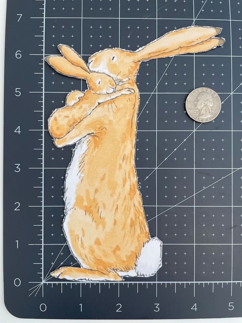 May include: A brown and white rabbit holding a smaller brown and white rabbit in its arms. The rabbits are both looking at the viewer. The larger rabbit has a white tail.