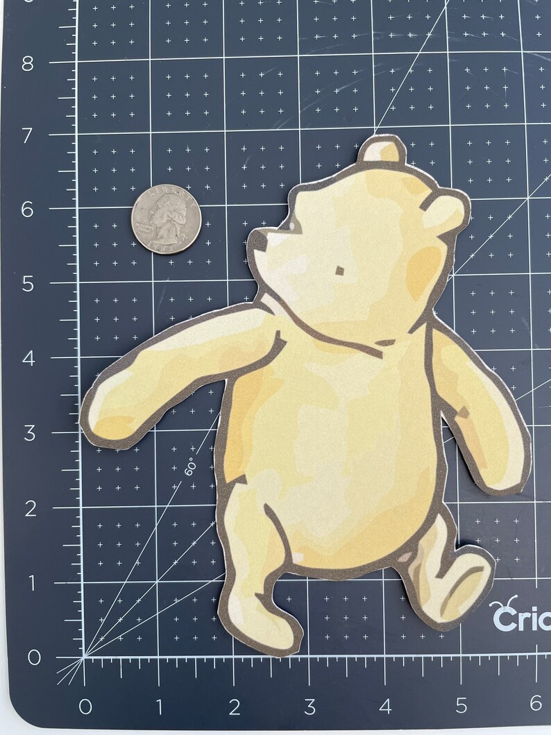 May include: A yellow Winnie the Pooh character cutout with a brown outline. The character is walking with its arms outstretched and is looking up.