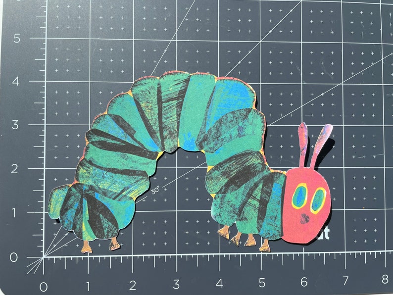 Pu&ograve; includere: Un bruco verde e nero con una testa rossa e occhi gialli. Il bruco &egrave; fatto di carta e ha un effetto 3D.