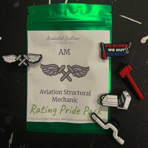 Può includere: Una bustina verde con cerniera che presenta un'etichetta bianca con la scritta "Accidental Creations Est. 2020 AM Aviation Structural Mechanic Rating Pride Pack 5 shoe charms that remind us what we love and hate about..." La bustina contiene cinque ciondoli colorati per scarpe: un martello rosso, una chiave inglese bianca con manico blu, una chiave inglese bianca con manico rosso, un'ala di aeroplano bianca con manico grigio e un'ala di aeroplano bianca con manico grigio.