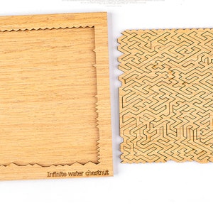 Puede incluir: Un rompecabezas de madera con un dise&ntilde;o de laberinto complejo y un marco a juego. El marco tiene un borde decorativo. Las piezas del rompecabezas son de color marr&oacute;n claro con l&iacute;neas grabadas en marr&oacute;n oscuro. El texto "Infinite water chestnut" est&aacute; impreso en el marco.