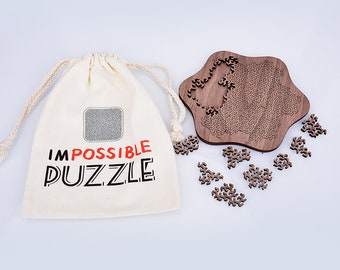 May include: A wooden jigsaw puzzle with an unusual shape and complex cut pieces. The puzzle is partly assembled, with some pieces scattered nearby. A canvas bag with the words "IMPOSSIBLE PUZZLE" is next to the puzzle.