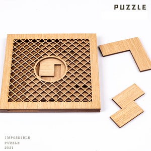 May include: A wooden puzzle with a square frame featuring a lattice design and a circular cutout. Two L-shaped pieces and one rectangular piece are separate. The word "PUZZLE" is at the top, and "IMPOSSIBLE PUZZLE 2021" is at the bottom.