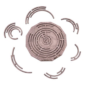 May include: A wooden puzzle featuring a circular maze design with concentric paths. Surrounding the maze are several curved wooden pieces. The puzzle is made of light brown wood and is set against a white background.