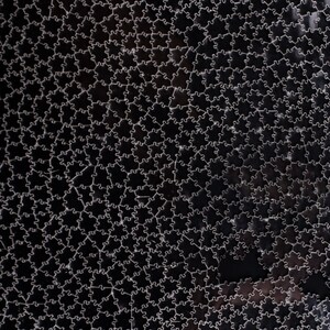 Puede incluir: Primer plano de una superficie negra cubierta por un patr&oacute;n de piezas de rompecabezas entrelazadas. Las piezas est&aacute;n delineadas en un color claro, creando un contraste. El efecto general es un dise&ntilde;o geom&eacute;trico texturizado.