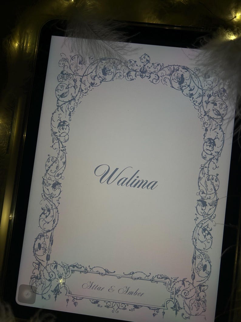Puede incluir: Una tarjeta de invitaci&oacute;n blanca con un borde floral azul y la palabra "Walima" en escritura elegante. Los nombres "Attar & Amber" se muestran en la parte inferior. La tarjeta est&aacute; sobre una bandeja negra con plumas.