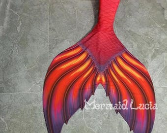 May include: Red, orange, and purple mermaid tail with a fin that has a pointed tip. The tail is made of fabric and has a scaly texture. The tail is lying on a gray tiled floor. The text "D1" is visible in the upper left corner of the image.