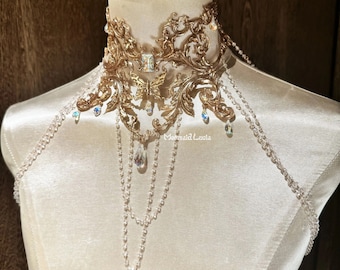 Puede incluir: Un collar de declaración dorado con un delicado dije de mariposa y detalles de cristal. El collar presenta un diseño de cadena en capas con múltiples hilos de cuentas.