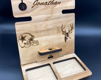 May include: A wooden phone stand with a personalized name "Jonathan" engraved on the top. It features a deer and a football helmet design. The stand has two slots for holding items.