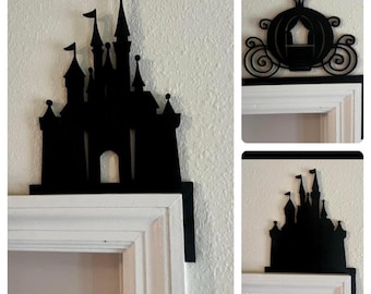 May include: Three black silhouette door toppers, one of Cinderella's carriage, one of a castle, and one of a castle with towers. The toppers are mounted above white door frames.
