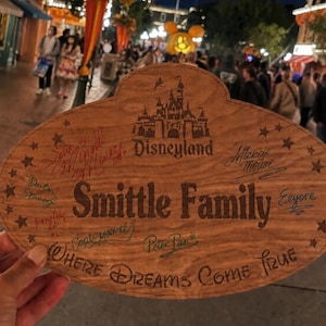以下が含まれることがあります： ディズニーランドの城のロゴ、「Smittle Family」、「Where Dreams Come True」という文字、そしてミッキーマウス、イーヨー、ピーターパンなどのキャラクターのサインが表面に刻印された楕円形の木製プレート。