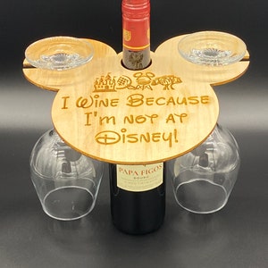 May include: Wooden wine holder shaped like Mickey Mouse ears with two glass holders and a bottle holder. The holder has the text "I wine because I'm not at Disney!" engraved on it.