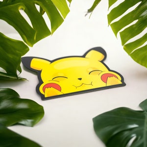 May include: A yellow cartoon character with closed eyes and a big smile. The character is a Pikachu from the Pokemon franchise. The character is printed on a sticker.
