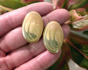 May include: A pair of gold oval-shaped earrings with a swirl pattern in shades of green and yellow.