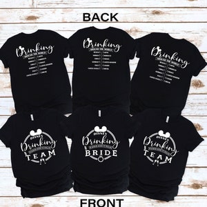 Puede incluir: Tres camisetas negras con texto y gráficos blancos. Las camisetas tienen el texto "Drinking Around the World" y una cabeza de Mickey Mouse. Las camisetas también tienen el texto "Disney Drinking Team", "Disney Drinking Bride" y "Disney Drinking Team".
