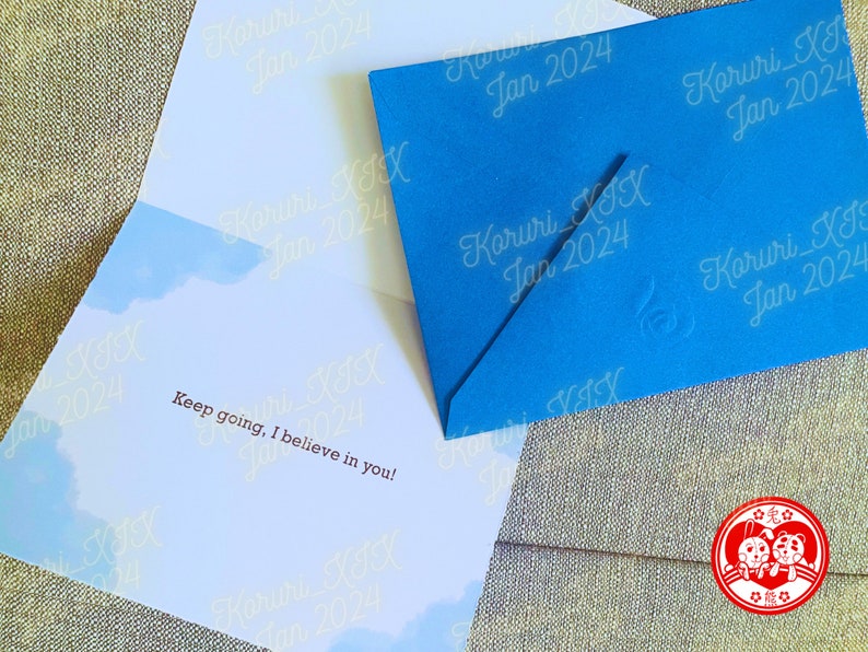 Puede incluir: Un sobre azul con el texto "Koruri_XI Jan 2024" repetido en el frente. El sobre est&aacute; abierto y el interior de la tarjeta es visible. La tarjeta tiene un fondo de cielo azul con nubes blancas y el texto "Keep going, I believe in you!" en letras marrones.