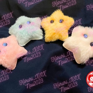 May include: Four plush star-shaped toys with embroidered eyes and a fuzzy texture. The stars are in pink, light blue, yellow, and white.