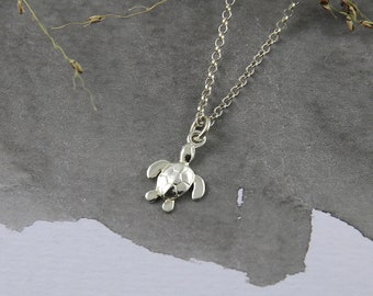 May include: A silver chain necklace with a small, detailed turtle pendant. The pendant is textured and has a realistic design.