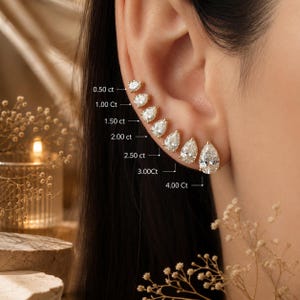 May include: A series of seven pear-shaped stud earrings in gold settings, arranged in a row along the earlobe. Each earring is labeled with its carat weight, ranging from 0.50 ct to 4.00 ct, showing the size progression of the clear, faceted stones.