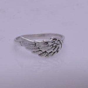May include: A silver ring with an angel wing design. The wing is detailed and textured.