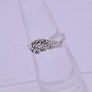 May include: A silver ring with a wing design. The wing is detailed and has a textured surface.