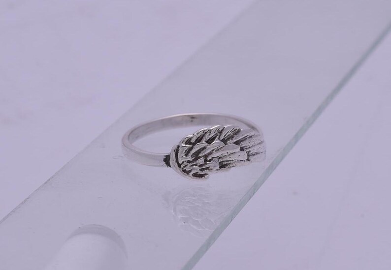 May include: Silver ring with a detailed wing design.