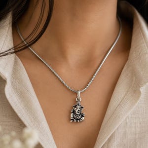 Pu&ograve; includere: Una collana color argento con un piccolo e dettagliato ciondolo della divinit&agrave; Ganesha. Il ciondolo &egrave; sospeso a una catena a serpente liscia e rotonda. Il metallo ha una finitura ossidata che mette in risalto gli intagli della testa di elefante.