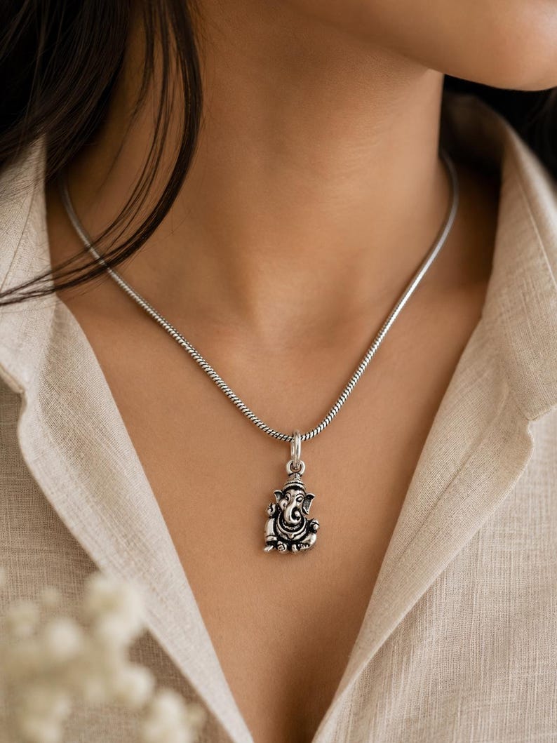 Pu&ograve; includere: Una collana color argento con un piccolo e dettagliato ciondolo della divinit&agrave; Ganesha. Il ciondolo &egrave; sospeso a una catena a serpente liscia e rotonda. Il metallo ha una finitura ossidata che mette in risalto gli intagli della testa di elefante.