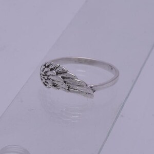 May include: A silver ring with an angel wing design. The wing is detailed and textured.