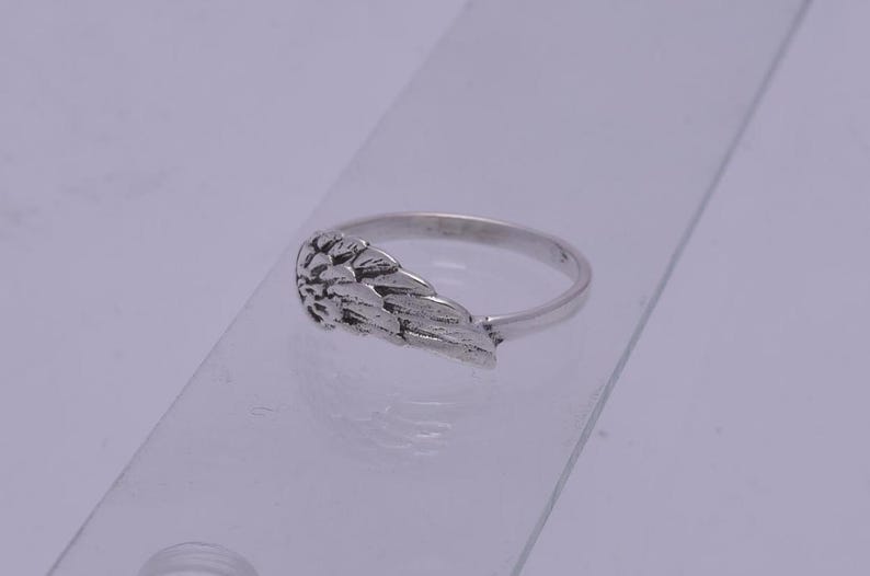 May include: A silver ring with an angel wing design. The wing is detailed and textured.
