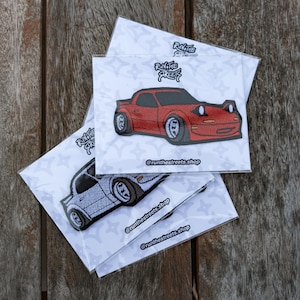 May include: Three white cards with a red and a white car embroidered on them. The cards have the text "Run the Streets" and "@runthestreets.shop" printed on them.