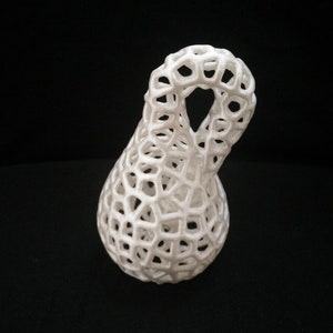 May include: A white ceramic sculpture with a lattice design. The sculpture is shaped like a pear with a loop at the top.