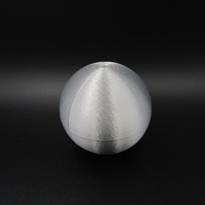 Op de afbeelding: Een witte, gladde, ronde bol met een kleine inkeping aan de bovenkant.