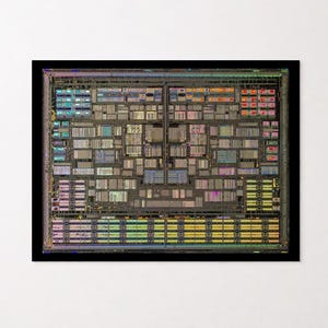 May include: A rectangular framed print featuring a high-resolution, top-down view of a complex computer processor die. The silicon chip displays intricate, multi-colored circuitry patterns in shades of blue, yellow, pink, and green on a dark base.