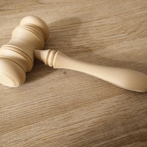 May include: A wooden gavel with a smooth, light brown finish. The gavel has a rounded head and a long, slender handle.