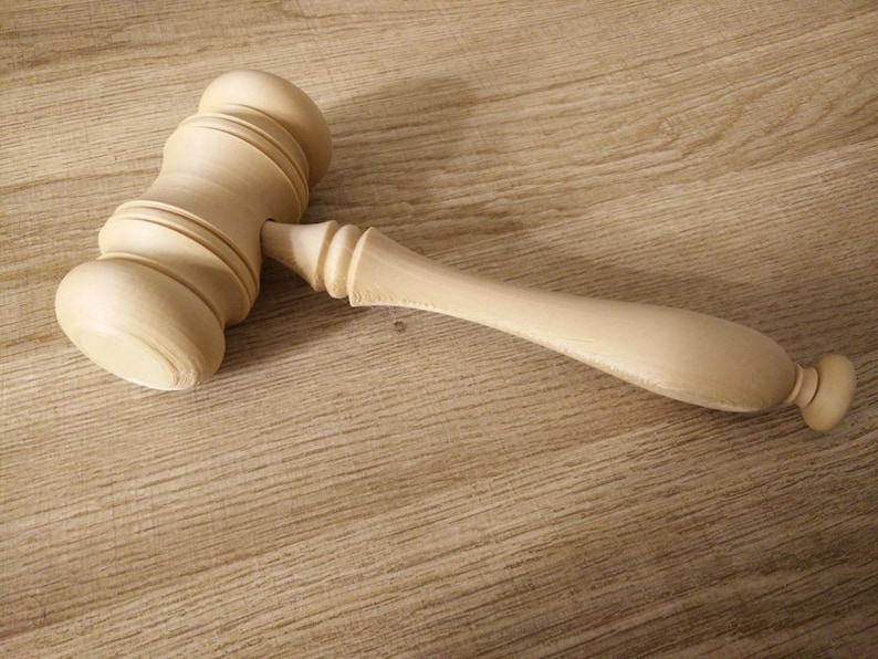 May include: A wooden gavel with a smooth, light brown finish. The gavel has a rounded head and a long, slender handle.