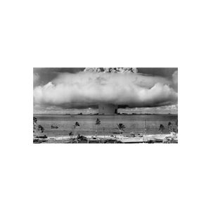 Puede incluir: Una fotografía en blanco y negro de una nube en forma de hongo que se eleva desde el océano después de una explosión nuclear. Palmeras bordean la playa en primer plano.