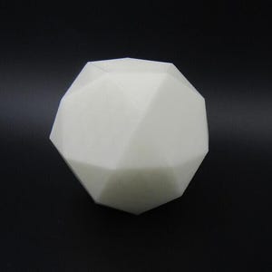 Könnte beinhalten: Ein weißes, geometrisches, vielseitiges Objekt, möglicherweise ein dekoratives Stück oder eine Skulptur, ist vor einem schwarzen Hintergrund zentriert. Die Form des Objekts erinnert an eine geodätische Kuppel oder ein komplexes Polyeder.