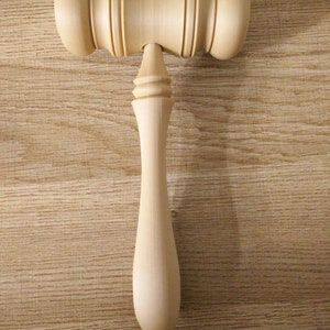 May include: A wooden gavel with a smooth, light brown finish. The gavel has a rounded head and a long, slender handle.