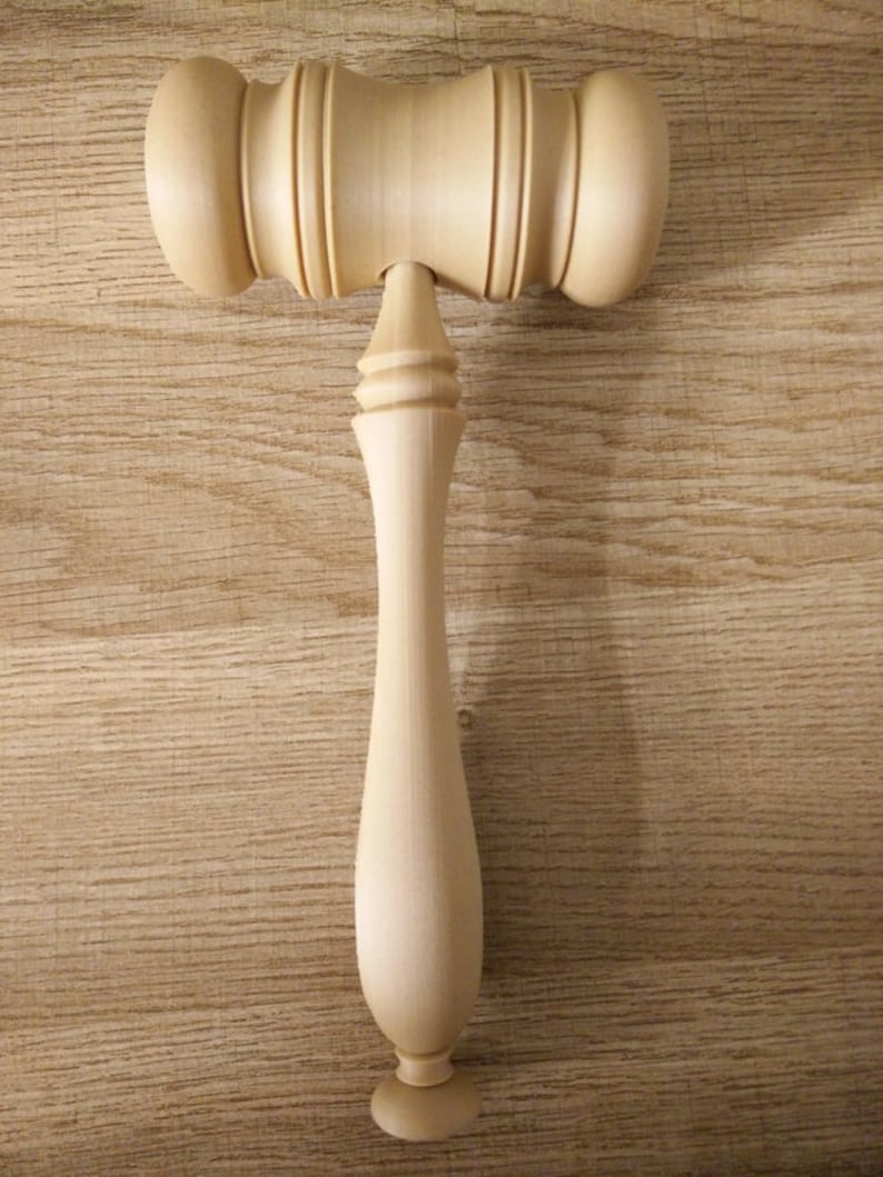 May include: A wooden gavel with a smooth, light brown finish. The gavel has a rounded head and a long, slender handle.
