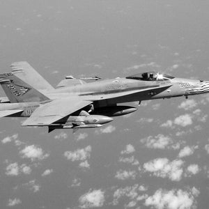 May include: A black and white photo of a US Navy F/A-18C Hornet fighter jet in flight. The jet is carrying two AIM-120 AMRAAM air-to-air missiles. The jet is labeled "BIG DUKE" and "300".