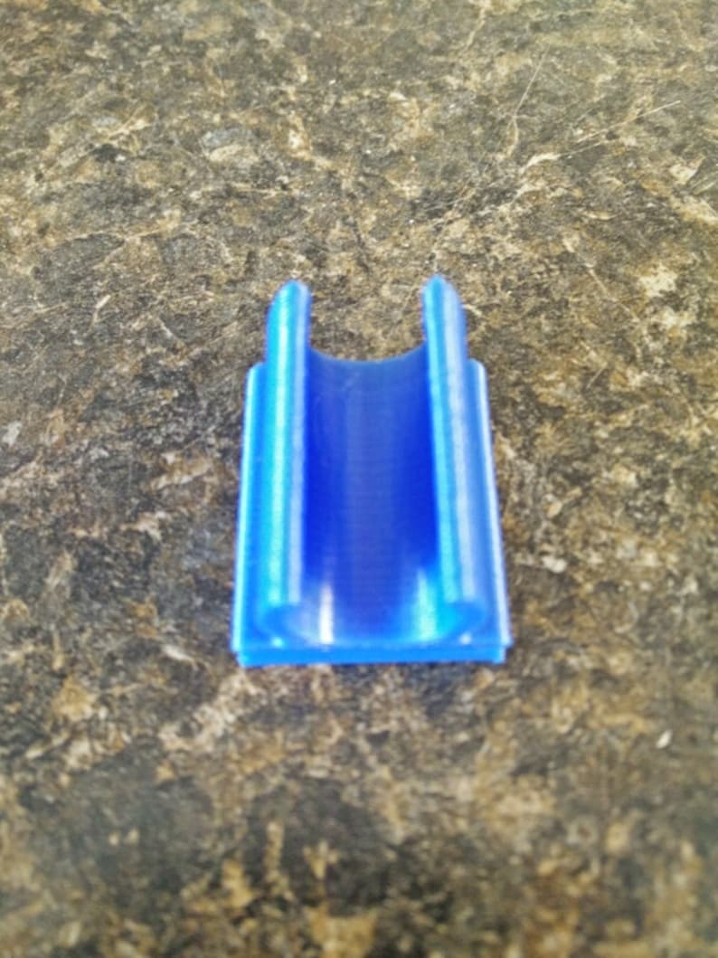 K&ouml;nnte beinhalten: Ein blauer U-f&ouml;rmiger Clip aus Kunststoff, m&ouml;glicherweise zum Organisieren von Kabeln oder Dr&auml;hten.